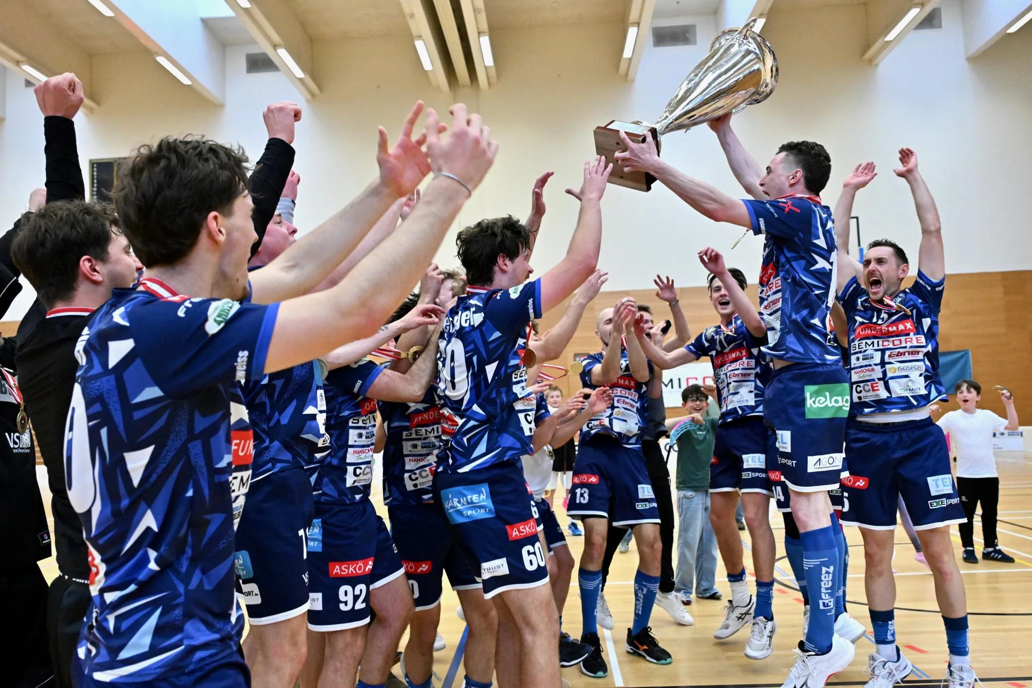 Die Mannschaft des VSV Unihockey jubelt in der Halle und streckt den Meisterpokal in die Höhe