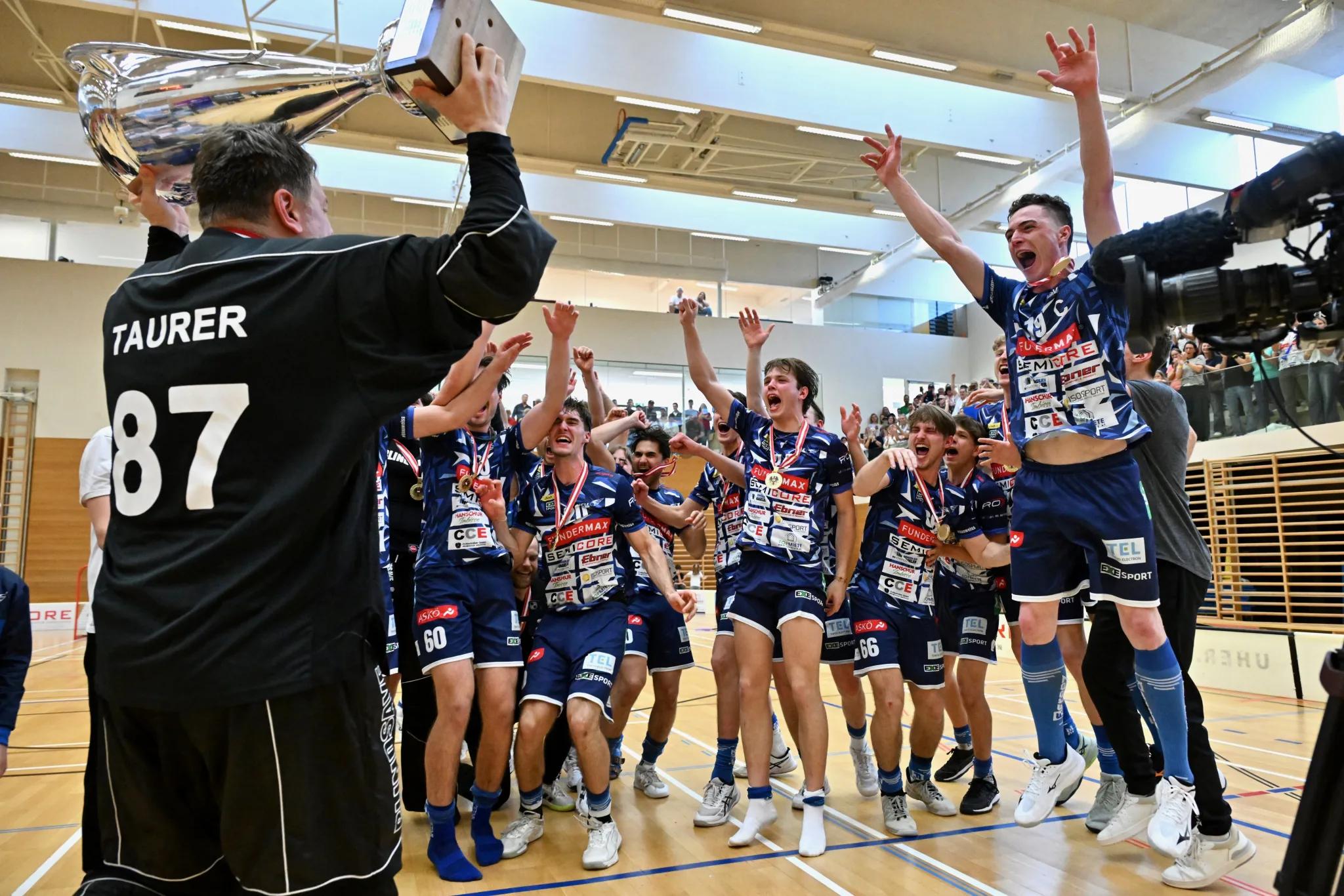 Spieler des VSV Unihockey jubeln mit dem österreichischen Meisterpokal in der Halle