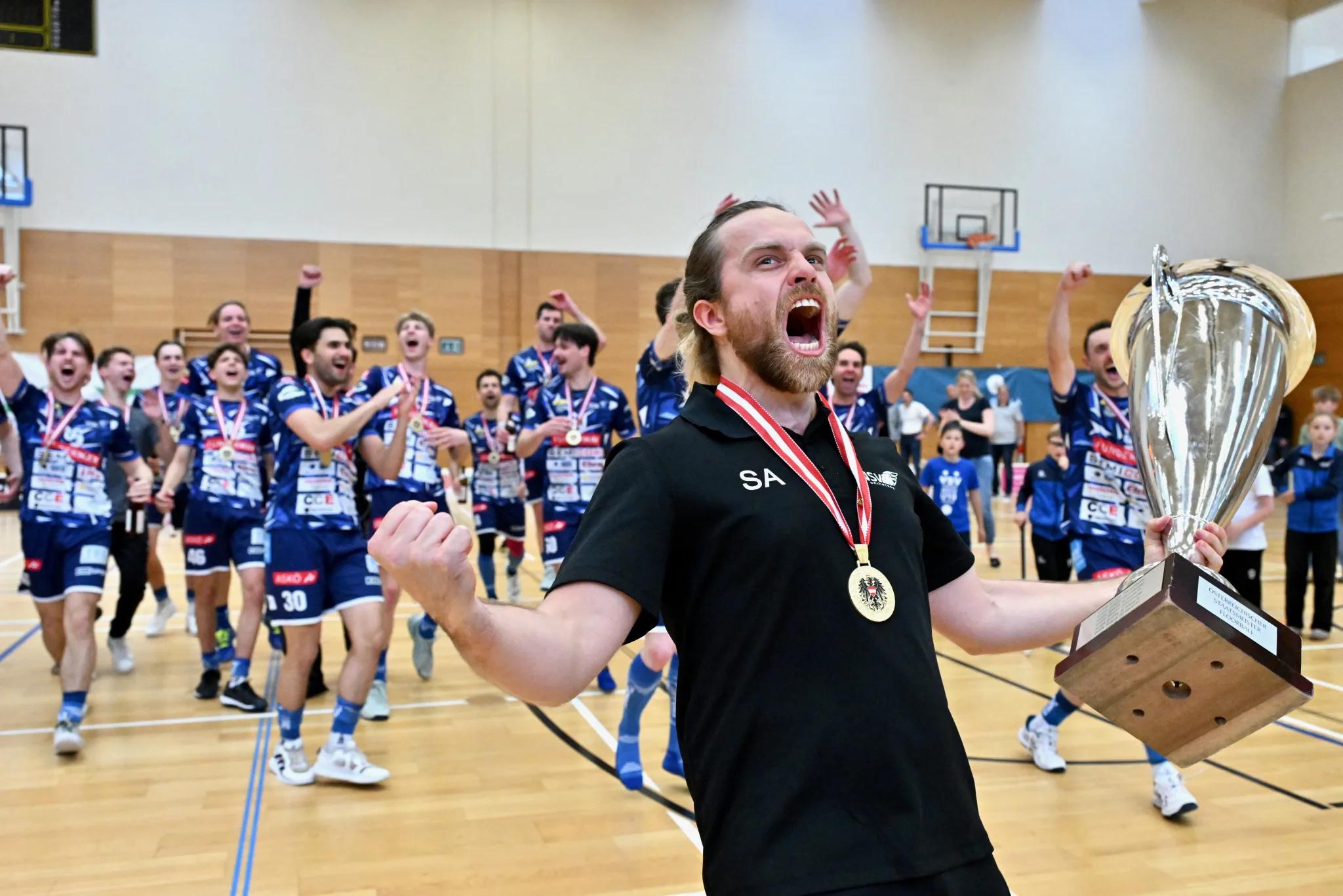Der Trainer des VSV Unihockey trägt den Meisterpokal, dahinter die jubelnde Mannschaft